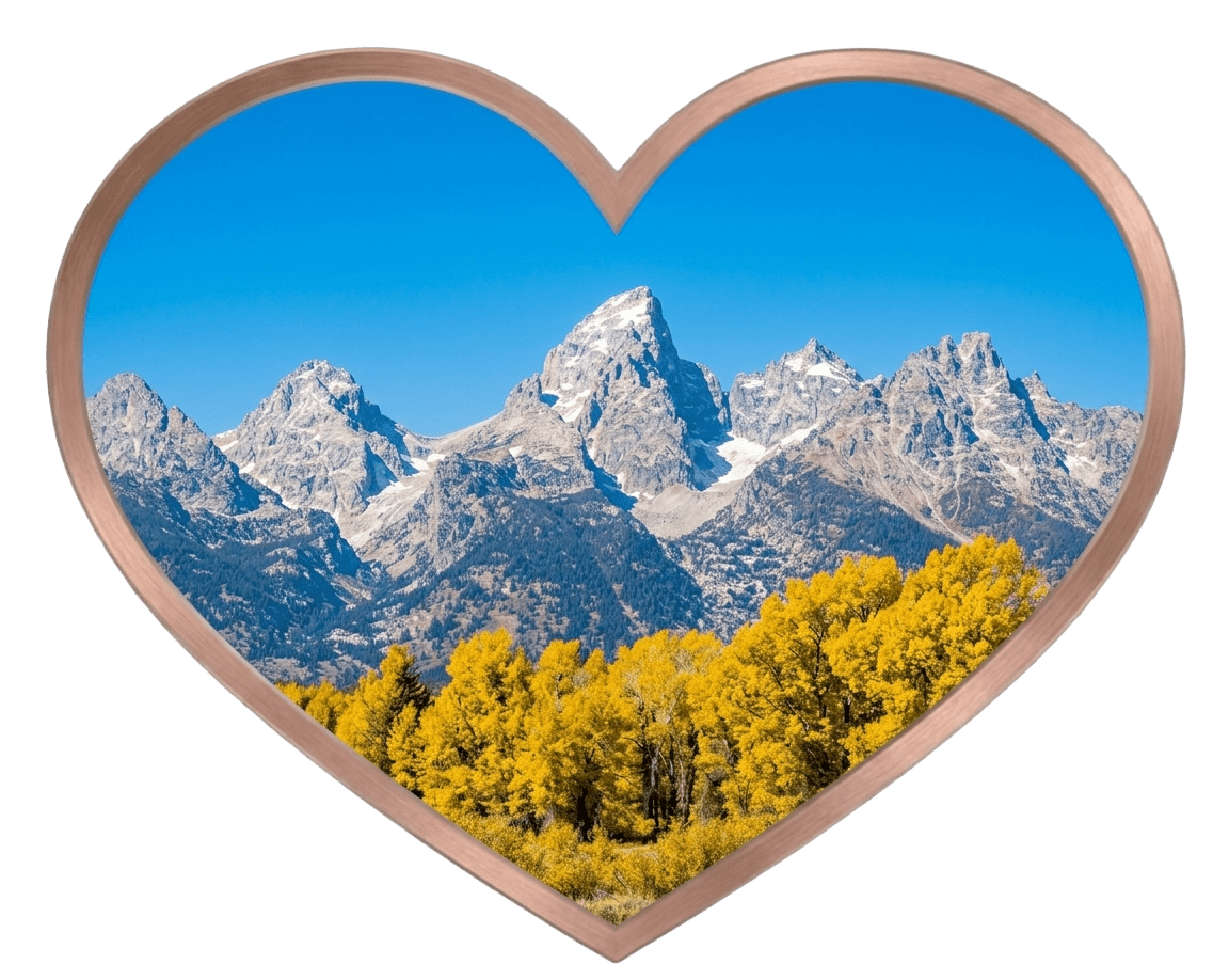 An epic landscape photo of the jagged, snow-capped Teton mountains in autumn, viewed inside a signature rose gold heart-shaped frame on a pure white background with gold sparkles, part of Holly Would Know's Great Northern Loop Cross Country Road Trip Part 2 blog series.