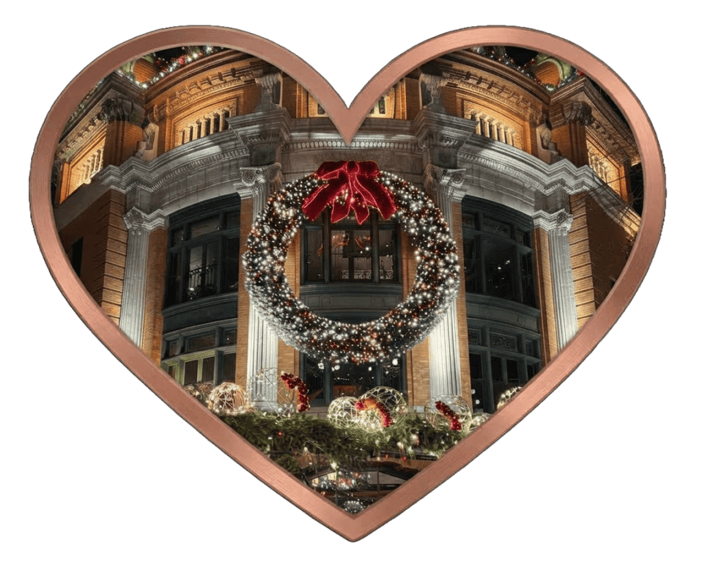 Featured photo of a massive illuminated Christmas wreath centered on the historic facade of the Palais Montcalm in Quebec City, Canada, framed in a copper-toned heart shape against a black background.